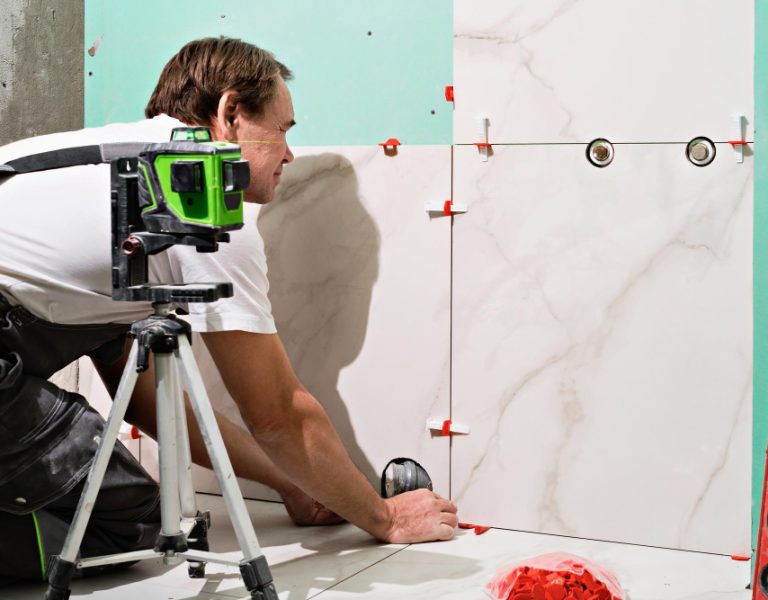 professional-master-man-laying-ceramic-tiles-wall-bathroom-portrait-experienced-repairman-laying-large-size-porcelain-tilesconstruction-worker-checking-tile-installation-with-laser-level